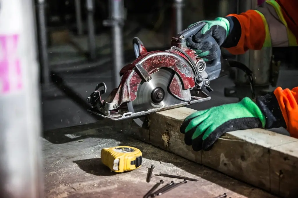 Builder cutting a timber beam with a circular saw on site