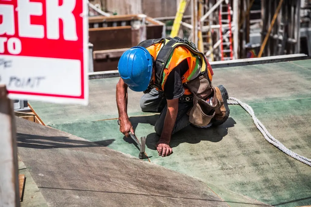 Builder in safety gear fixing a floor panel